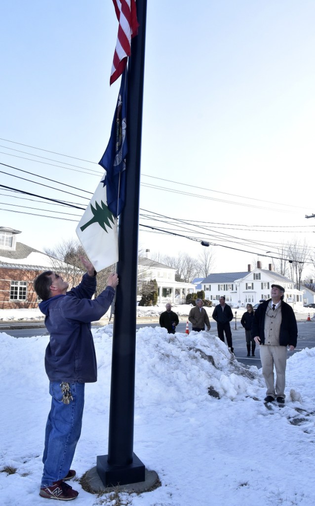 Tom Batchelder Jr. hoists a replica of the original state of Maine flag used from 1901 through 1909 up a flagpole under the current state flag and the American flag outside the Somerset Superior Courthouse in Skowhegan on Wednesday.