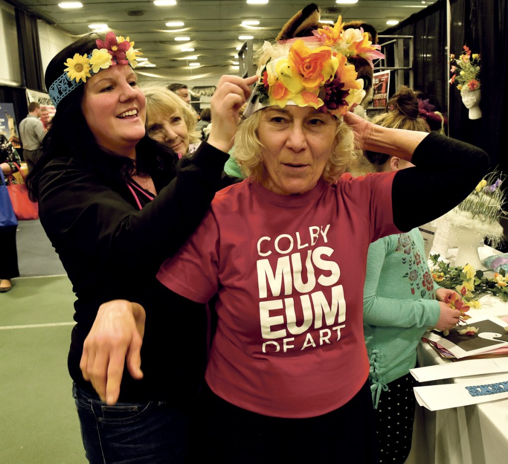 Tonya Clark, left, of T-Mobile, fastens a spring bonnet on Natty Lazavian, of the Colby College Museum of Art, on Thursday during the Business to Business event at Colby College in Waterville. The colorful bonnets were courtesy of the Waterville Creates! art program.