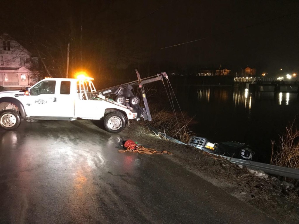 A Ford F-150 pickup truck is hauled out of the Kennebec River early Friday. A wet, cold William Sweet claimed to be a passenger in the truck, but police summoned him on charges of operating under the influence and operating without a license.