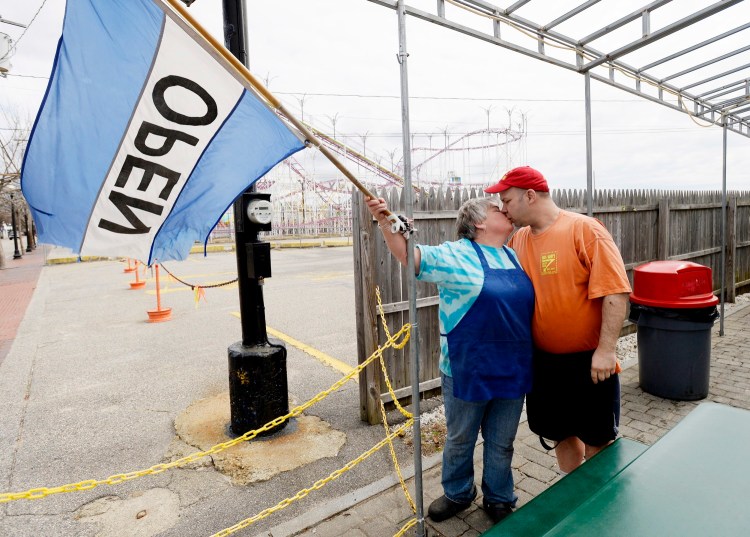 Brian Coddens (Hoss) gives a kiss to Deena Eskew (Mary) as they put up the "open" flag for the last time in 2015 at their restaurant in Old Orchard Beach.
