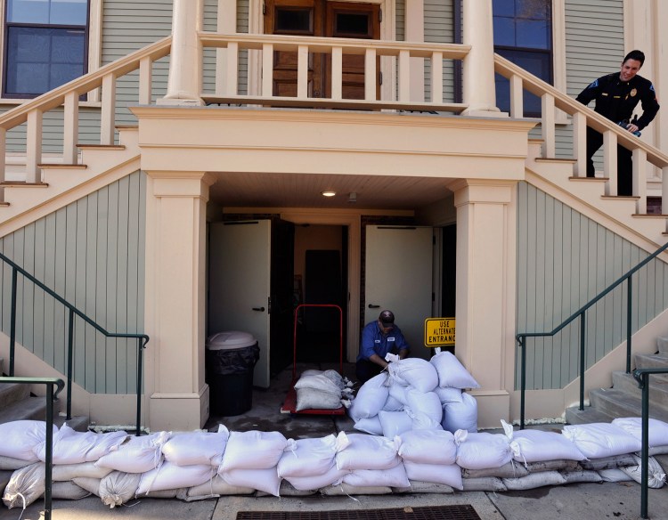 Paulo Andrade moves sand bags around the lower entrance to the town hall in Provincetown, Mass., on Thursday in preparation for the approaching storm.