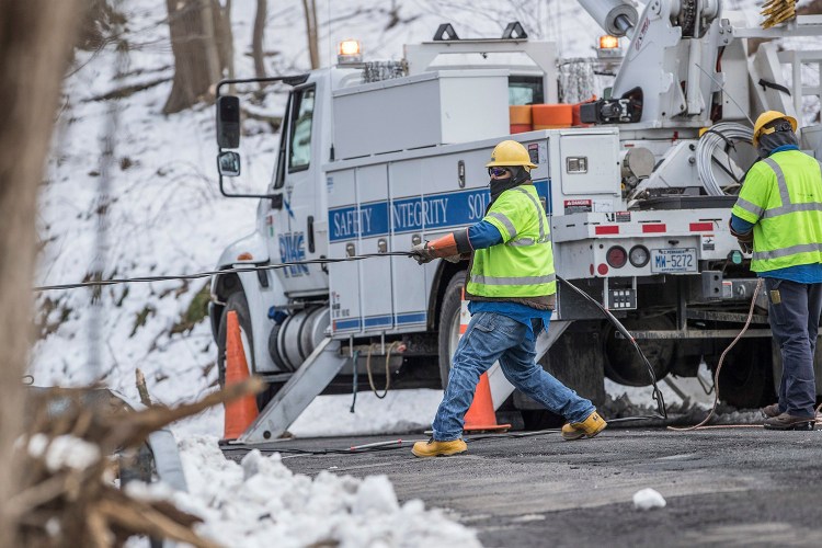 Crew members from Pike electric company from Maryland pull a downed power line on New Road in Aston, Pa., in order to reconnect it on Thursday. 