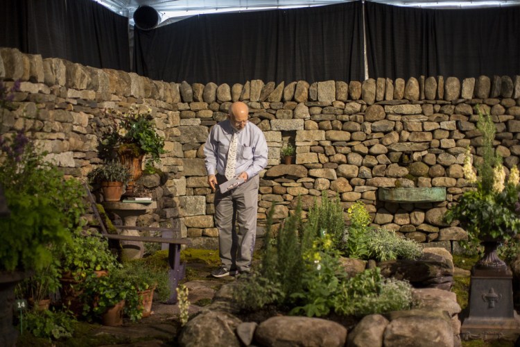 Gary Fish, state horticulturist, judges the Maine Stonework garden display at the 2018 Maine Flower Show.