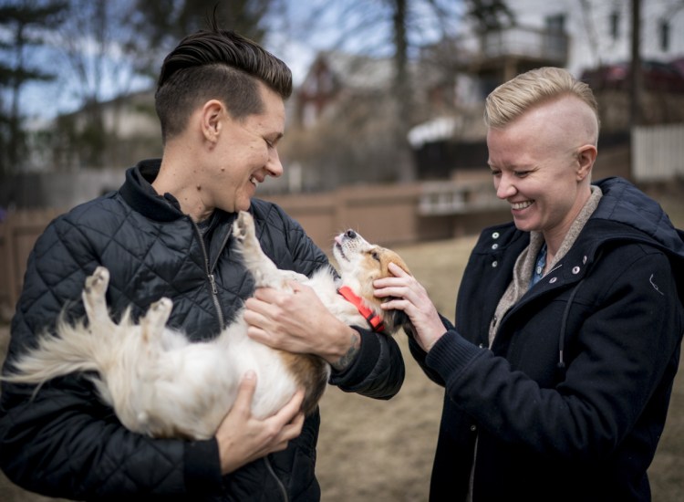 LK Weiss, left, and her wife, Laura Kloosterman, play with Duck in their yard in Bayside. They adopted her from the Animal Refuge League of Greater Portland, which has accepted hundreds of dogs from the island.