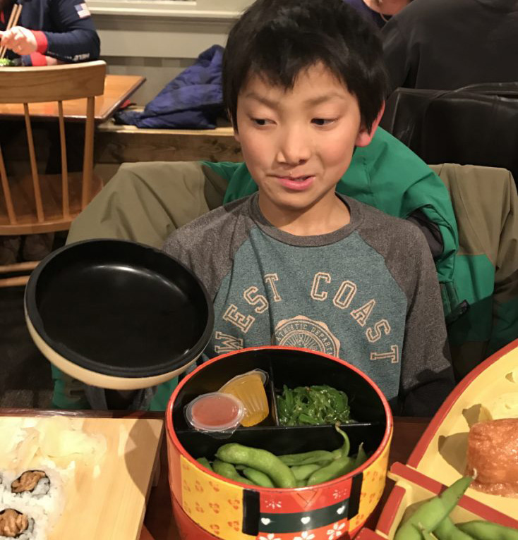 Peter Ericson, 9, brings his best side-eye game to Yosaku, glancing doubtfully at some sushi.