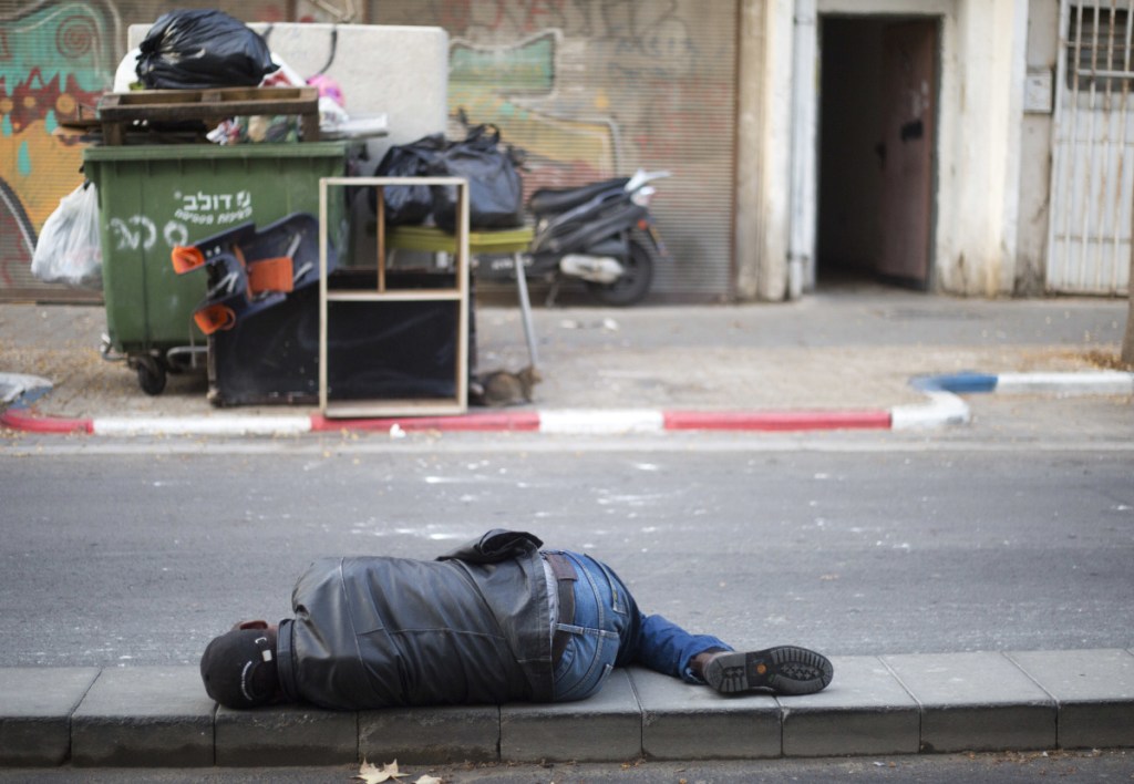 An African migrant sleeps in a street in Tel Aviv, Israel. Prime Minister Netanyahu canceled his plan to help resettle migrants.
