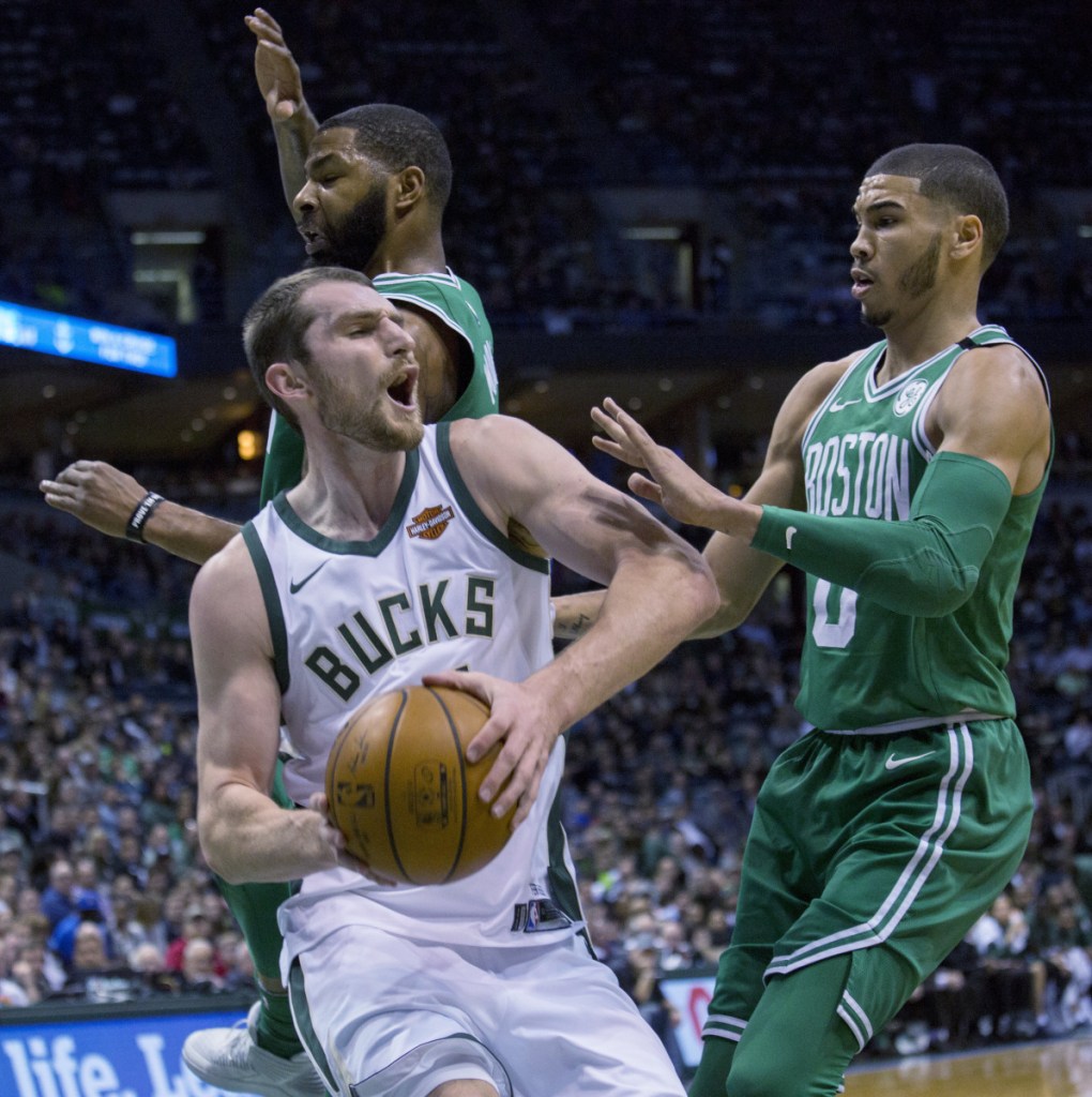 Milwaukee center Tyler Zeller, center, is defended by Boston forward Marcus Morris, left, and Jayson Tatum, right, during Tuesday's game in Milwaukee.