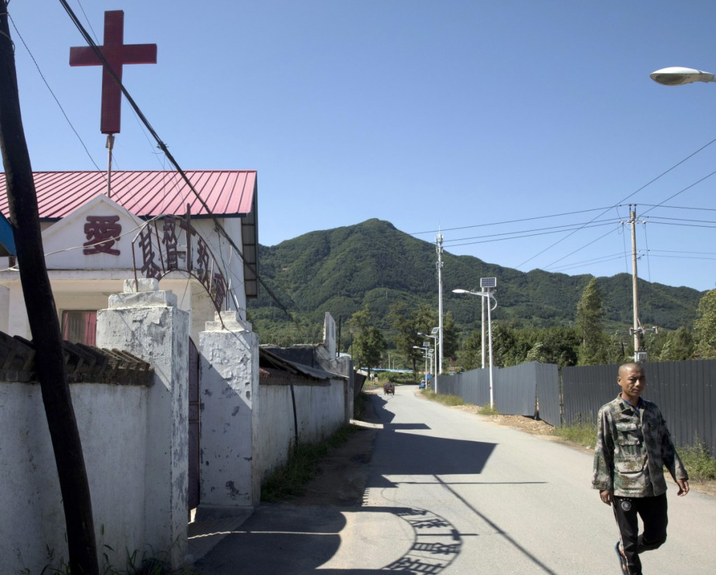 A cross on a church beckons believers in a border town in northeastern China's Jilin province, where the risks are high for missionaries offering prayer and guidance to North Koreans passing by. It is dangerous work for all parties and a South Korean pastor says at least 10 front-line church people have died mysteriously in recent years. At left, the Rev. Kim Kyou Ho, head of the Chosen People Network, shows a portrait of one of them, the Rev. Han Chung-ryeol, found dead in 2016.
Associated Press/Ng Han Guan/Ahn Young-joon
