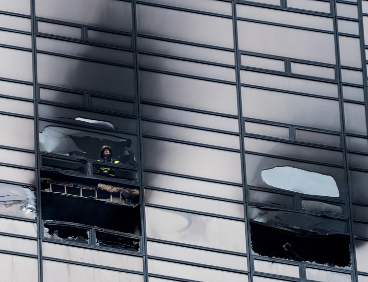 A firefighter looks out the window of a Trump Tower apartment where a 66-year-old art collector who spent time with Andy Warhol was killed in a fire.