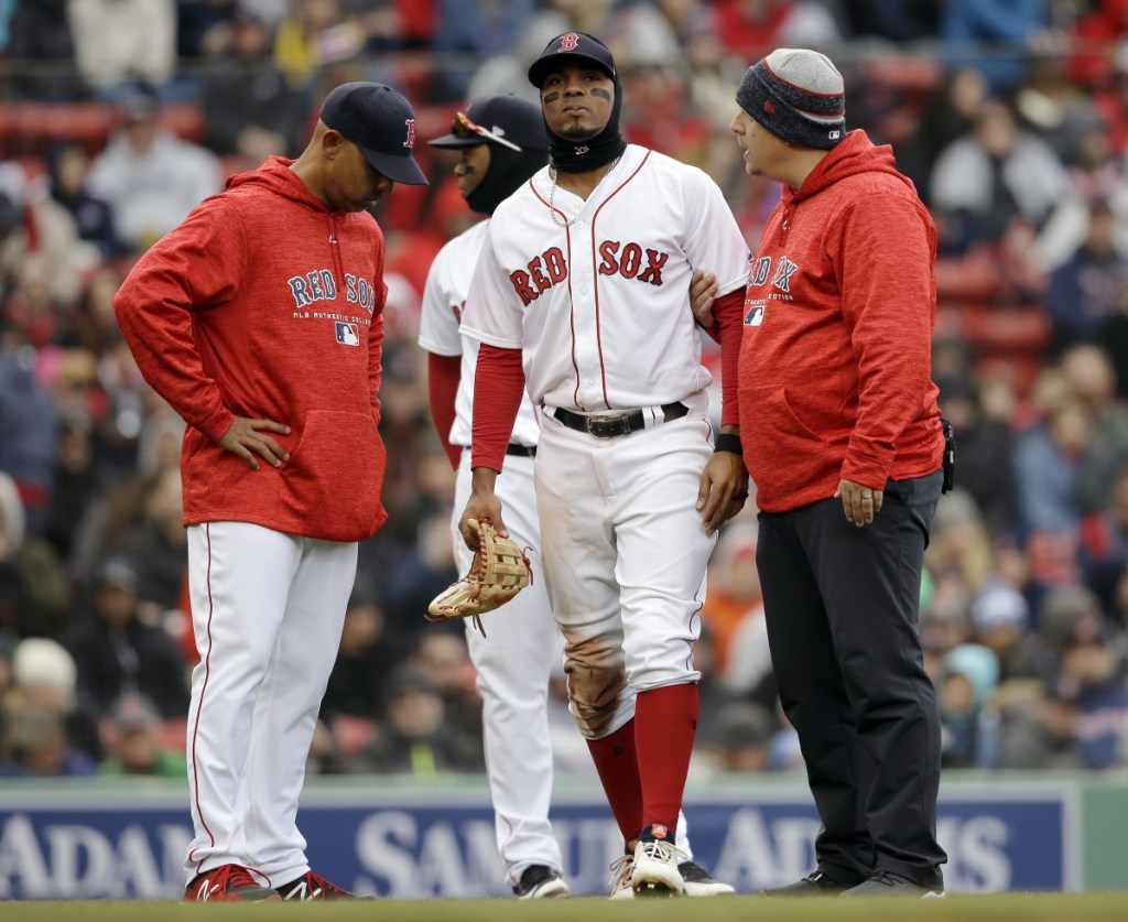 Xander Bogaerts of the Boston Red Sox limps off the field Sunday as Manager Alex Cora, left, looks on. Bogaerts injured his left ankle while sliding for an errant ball.