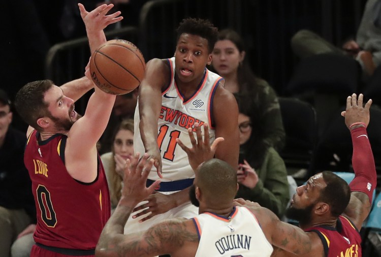 Knicks guard Frank Ntilikina makes a pass to center Kyle O'Quinn while being defended by Cleveland's Kevin Love, left, and LeBron James, right, on Monday in New York.