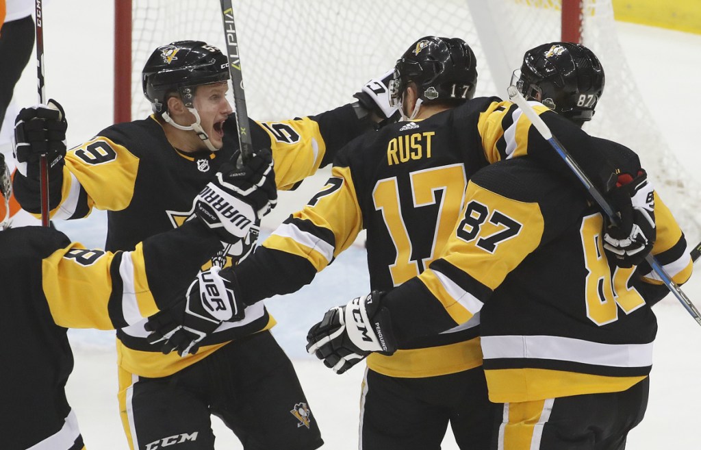 Bryan Rust, center, celebrates with Jake Guentzel, left, and Sidney Crosby after scoring a first-period goal Wednesday in Pittsburgh's 7-0 win over the Flyers in Game 1 of their first-round series.