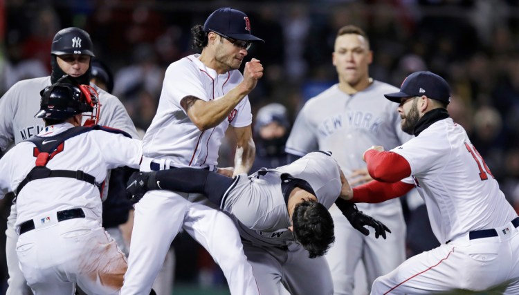 Boston Red Sox relief pitcher Joe Kelly, left, throws a punch at New York Yankees' Tyler Austin, center, as they fight during the seventh inning of Wedesday night at Fenway Park in Boston. Kelly has been suspended six games and Austin five.