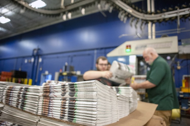 Production workers stack newspapers onto a cart at the Janesville Gazette Printing & Distribution plant in Janesville, Wis., earlier this week.