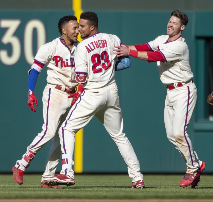 Aaron Altherr celebrates with Phillies teammates J.P. Crawford, left, and Andrew Knapp after his 11th-inning single Sunday beat Pittsburgh, 3-2.