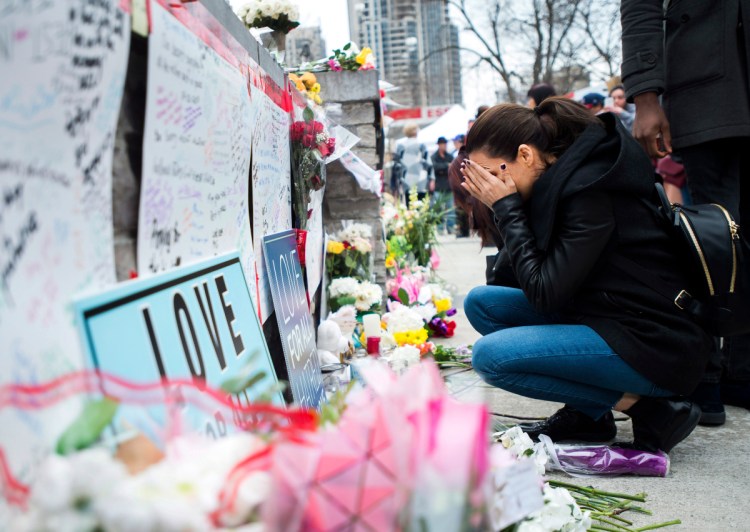 A women fights back tears at a memorial along Yonge Street on Tuesday in Toronto, the day after a driver drove a van down sidewalks, striking and killing numerous pedestrians in his path.