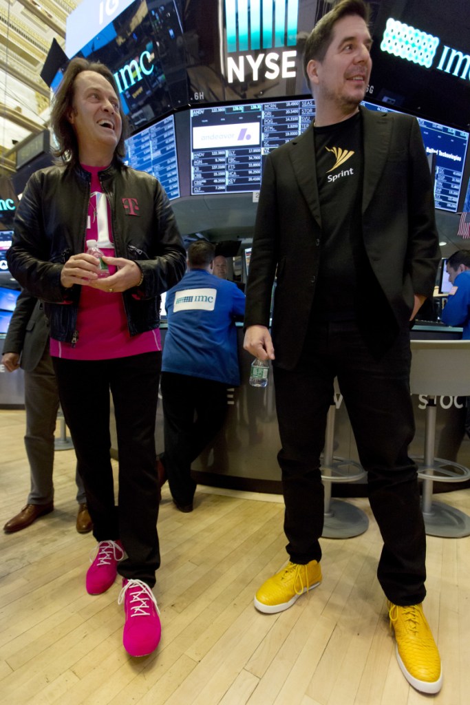 T-Mobile CEO John Legere, left, and Sprint CEO Marcelo Claure wear their signature colored shoes Monday on the first day the New York Stock Exchange was open after T-Mobile and Sprint said they would merge into a company with 127 million customers.