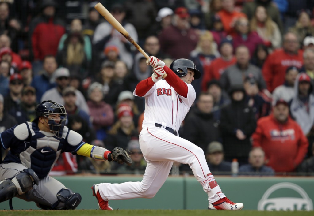 Boston's Andrew Benintendi, right, hits an RBI-double as Tampa Bay's Jesus Sucre, left, looks on in the eighth inning Sunday in Boston.