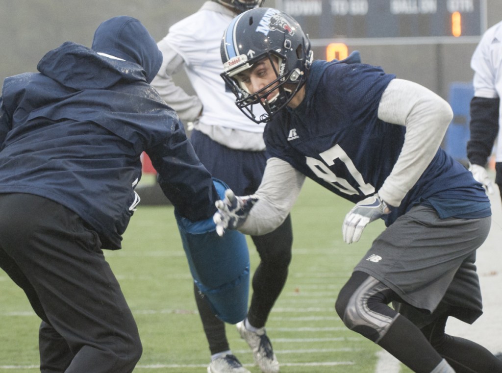 UMaine football player Hunter Smith joins his teammates on the rain soaked field for the first spring practice Wednesday in Orono.