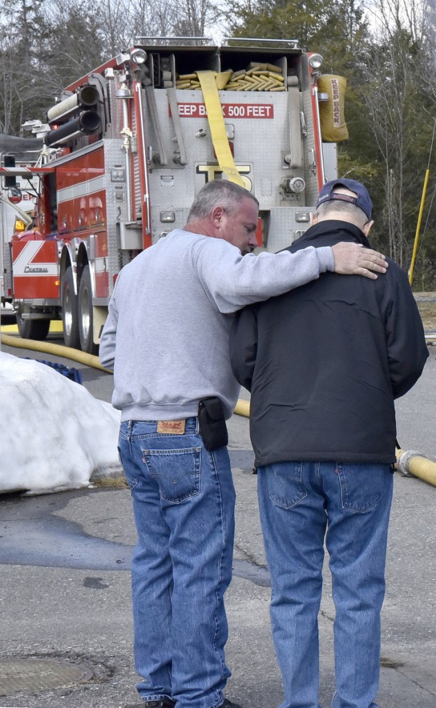 Dennis Wright, left, comforts his neighbor Ron Goguen on Thursday as firefighters from several departments battle a smoky fire that destroyed a mobile home rented by Goguen and his wife, Sandra, at China Lake Park in Vassalboro.