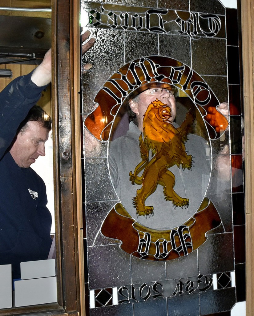Old Mill Pub owner Greg Dore is seen in the center of a new stained glass window he and Bill Epp, left, installed at the Skowhegan restaurant on Monday. The original stained glass was removed and given to the McCarthy family who previously owned the business.