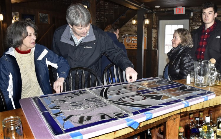 McCarthy family members, from left, Judie, Rick, Julie and Kael, look over the stained glass window that greeted customers inside the Old Mill Pub in Skowhegan that the family once owned after it was removed on Monday. Current owner Greg Dore gave the family the original window and replaced it with a new one.