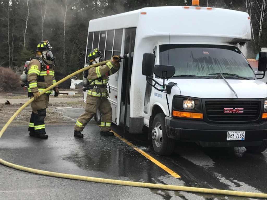 Firefighters Jeremy Manzer and Miranda Taylor, of the Augusta Fire Department, work to extinguish a fire that started Tuesday in a shuttle bus on the Augusta campus of MaineGeneral Medical Center.
