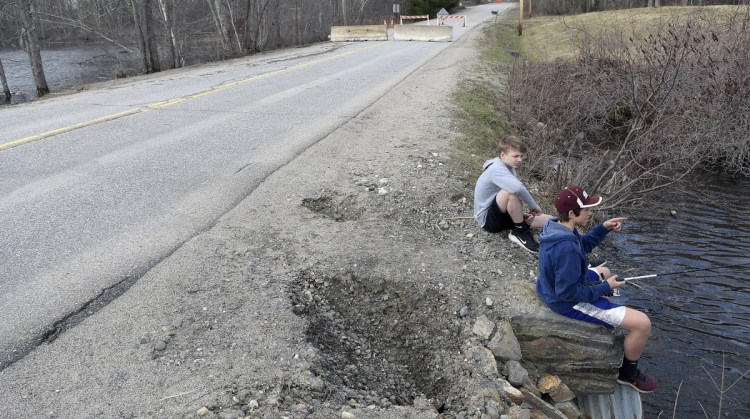 Cam Armstrong, right, and Manny Calder fish Wednesday atop a culvert that washed out, forcing the closure of Sanborn Road in Monmouth. The road is closed until the town figures out how finance repairs. The Monmouth Academy students were searching for fish during spring break.