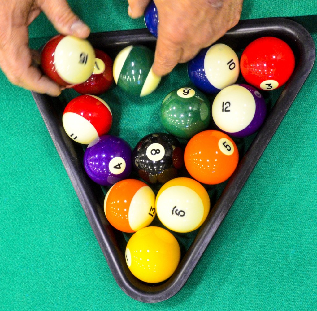 A competitor racks balls to start another round during a pool tournament on Sunday in the Augusta Armory.