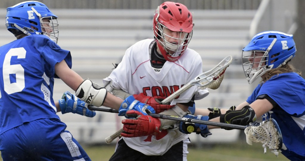 Cony's Micquais Baisuz runs between the defense of Erskine's Kyle Kirkpatrick, left, and Logan Poulin during a lacrosse match Wednesday in Augusta