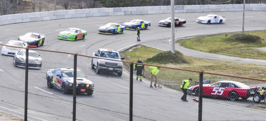 Cars circle slowly under a yellow caution flag as track workers clean up after the 55 driven by Bob Crocker spun out in turn four during the Super Street feature race Saturday at Wiscasset Speedway.