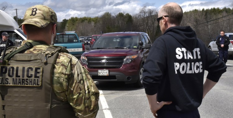 Police from numerous local, state and federal agencies watch as murder suspect John Williams, in cruiser, is taken from the scene in Fairfield after being apprehended on Saturday following a four-day manhunt for the killing of Somerset Cpl. Eugene Cole on April 25.