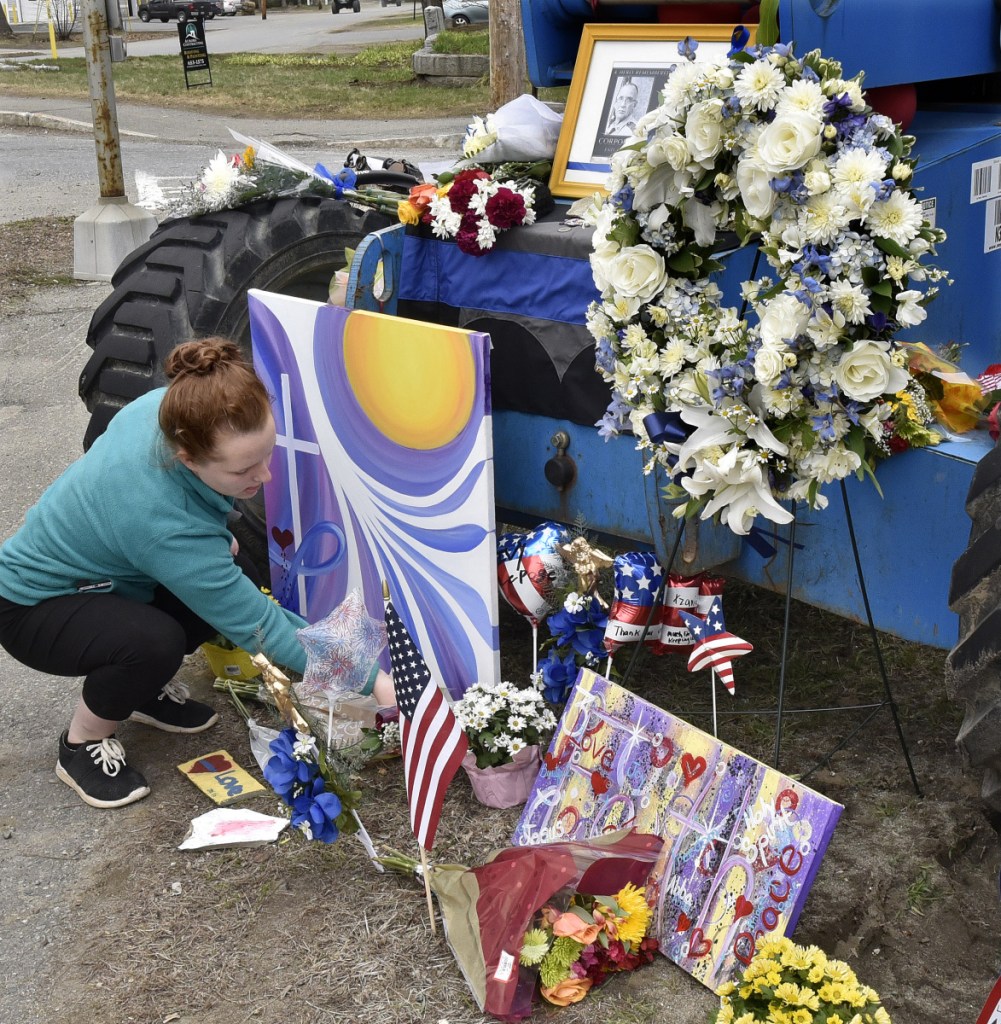 Angela Gilman, of Norridgewock, places flowers at a growing memorial for slain Somerset County Deputy Cpl. Eugene Cole in the center of town on Sunday. "I've known him for a long time and he was a close friend," Gilman said as others arrived to show respect for Cole.