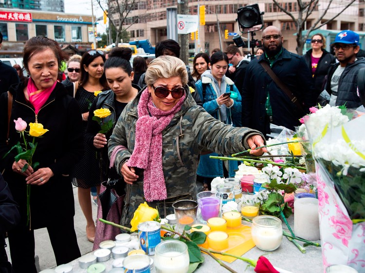 A tearful Ozra Kenari places flowers Tuesday at a memorial for the victims the day after a driver drove a van onto a crowded sidewalk in Toronto, killing 10 people.