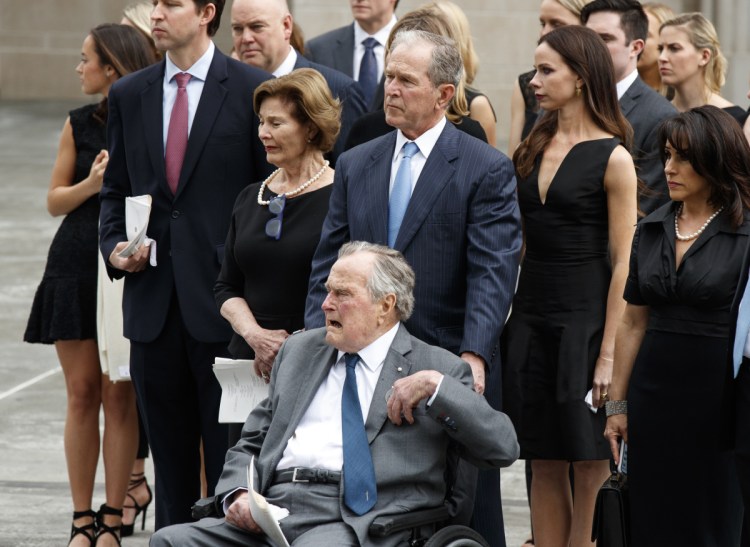 Former President George H.W. Bush, in wheelchair, his son former President George W. Bush, and other family members watch as the casket of former first lady Barbara Bush is loaded into a hearse at St. Martin's Episcopal Church in Houston on April 21.