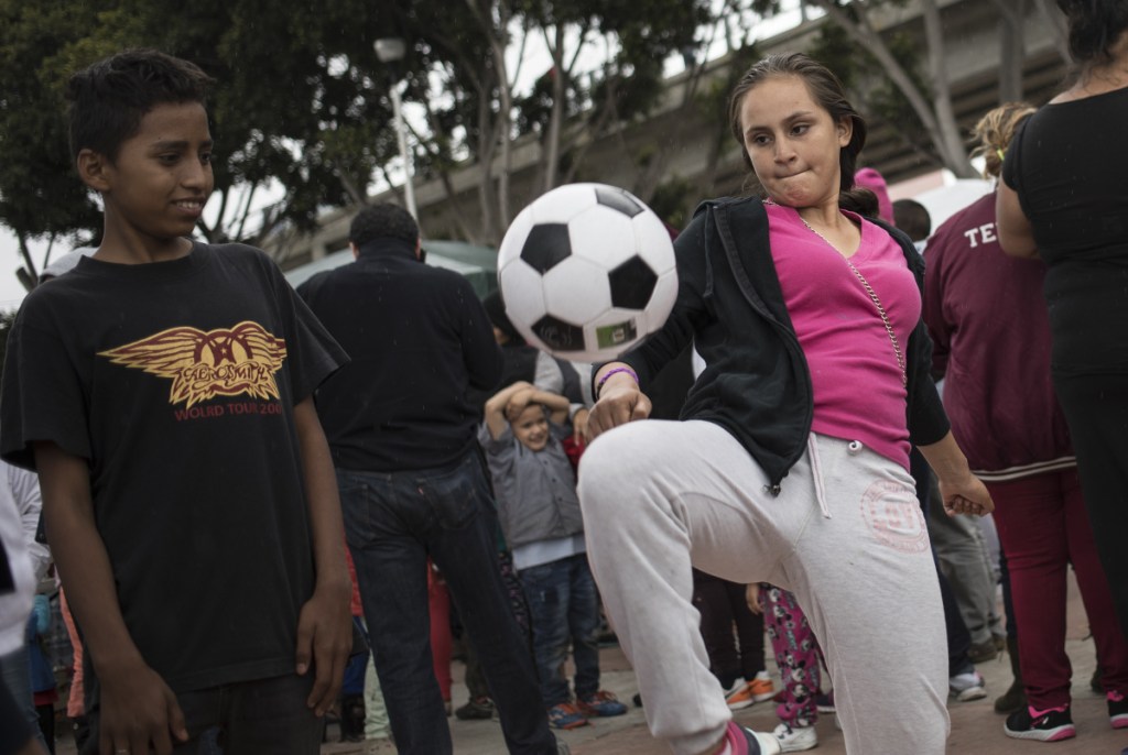 A migrant who traveled with the caravan of Central American migrants juggles a soccer ball where the group set up camp to wait for access to request asylum in the U.S.