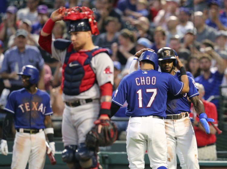 Boston catcher Christian Vazquez stands by the plate as Texas' Shin-Soo Choo, 17, and Delino DeShields, right rear, celebrate after scoring on Nomar Mazara's double during the third inning Thursday night at Arlington, Texas.