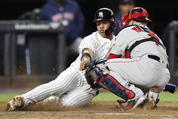 Boston catcher Christian Vazquez tags New York's Gleyber Torres out at home plate as Torres tried to score on Aaron Judge's seventh-inning, RBI single in a Tuesday's game in New York.