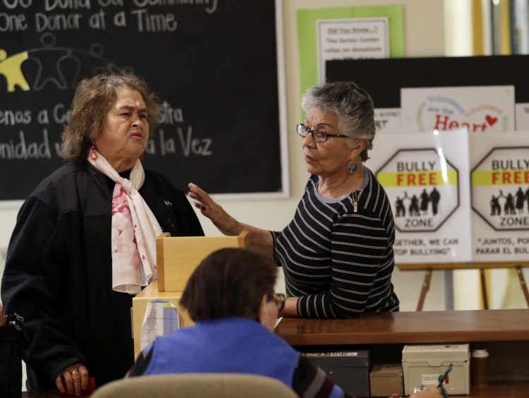 Two women talk in front of anti-bullying signs at the On Lok 30th Street Senior Center in San Francisco. After problems at the facility, staff received 18 hours of training that included lessons on what constitutes bullying and how to manage such conflicts.