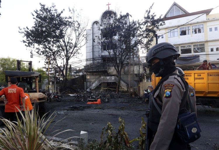A police officer stands guard at one of the sites of church attacks in Surabaya, East Java, Indonesia, on Sunday. Suicide bombers on motorcycles and including a woman with children targeted Sunday Mass congregations in three churches in the country's second-largest city, killing at least seven people and wounding dozens in one of the worst attacks on the country's Christian minority, police said.