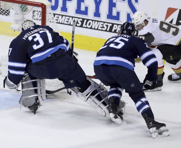 Las Vegas' Tomas Tatar, right, scores on Winnipeg goalie Connor Hellebuyck, left, with Paul Stastny on Monday in Winnipeg, Manitoba. The game was in progress at deadline.