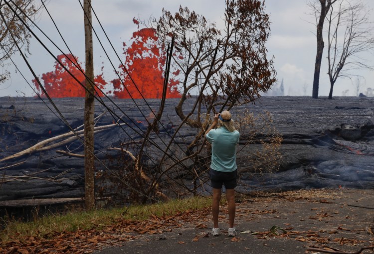 Jim Carpenter photographs lava erupting from fissures in the Leilani Estates subdivision near Pahoa, Hawaii, on Tuesday. The Kilauea volcano lava has destroyed nearly 50 structures.