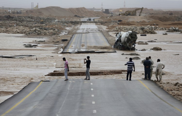 People visit a road cut by floodwaters after Cyclone Mekunu in Salalah, Oman, on Saturday. The cyclone blew into the Arabian Peninsula, drenching Oman and Yemen with rain and cutting off power lines. 