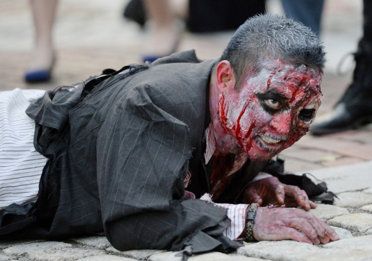 Brian Noyes of Portland  crawls through Monument Square as he performs during a zombie dance event in October 2015.