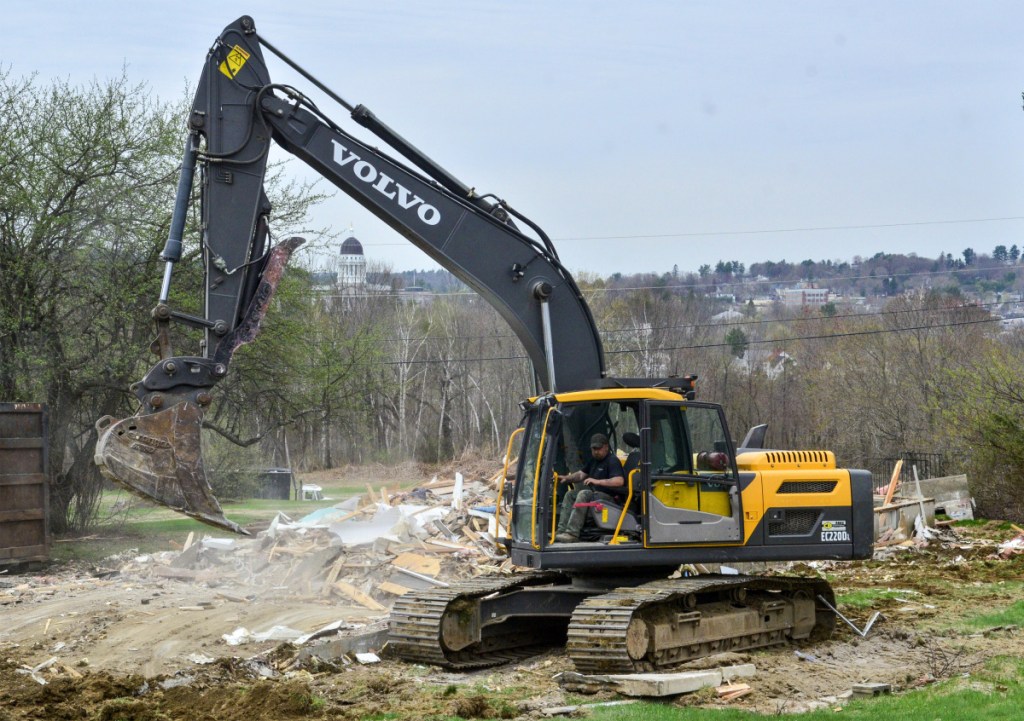 An excavator operator cleans up on Thursday after demolishing one of two houses on Independence Drive in Augusta.