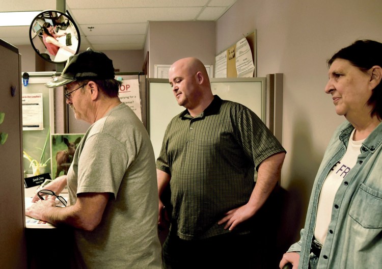 Patrick Roy, left, speaks with Waterville Deputy Clerk Sarah Cross, seen in mirror, at City Hall while filling out paperwork for a petition to recall Ward 7 Councilor Jackie DuPont on Monday. Also participating in the recall effort is Roy's son Andy and wife Marilyn.