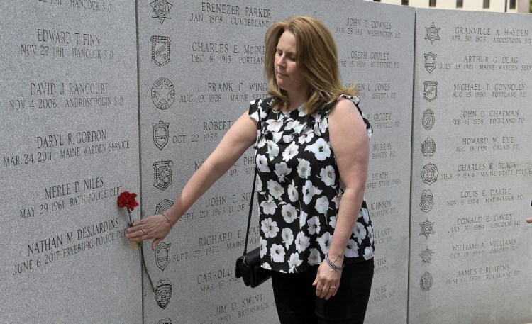 Nicole Desjardins places a carnation next to the name of her son, Nathan Desjardins, of the Fryeburg Police Department, at the Maine Law Enforcement Officer's Memorial in Augusta on Thursday. Desjardins, who died during a water rescue in 2017, was the 85th name to be added to Memorial.