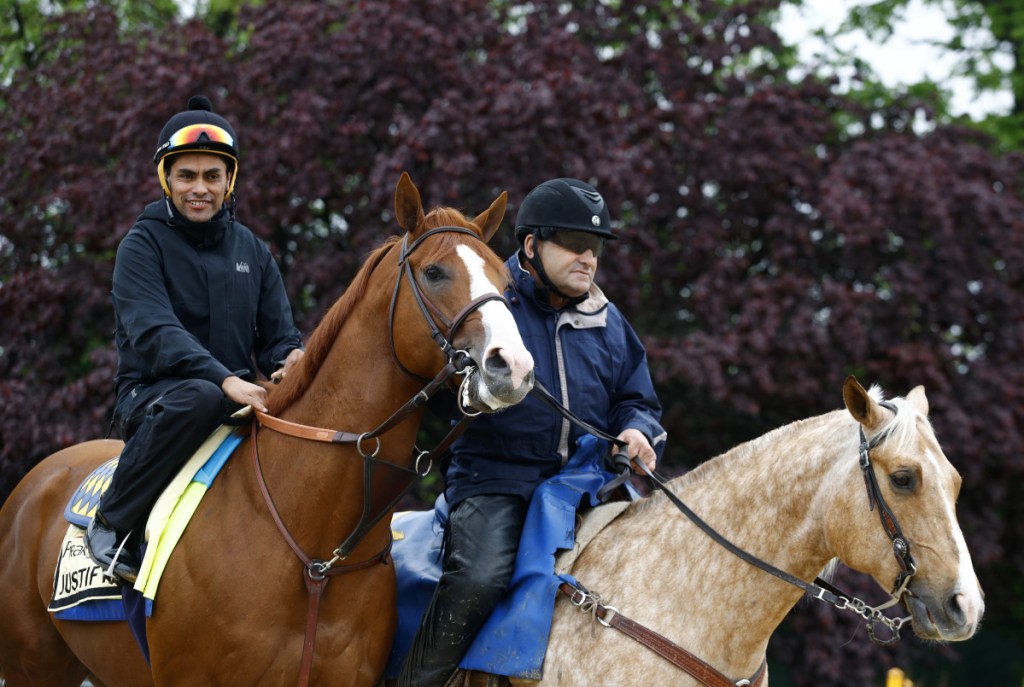 Kentucky Derby winner Justify, left, with exercise rider Humberto Gomez aboard, is escorted to the track for a workout Thursday at Pimlico Race Course in Baltimore. The Preakness Stakes is scheduled to take place Saturday.