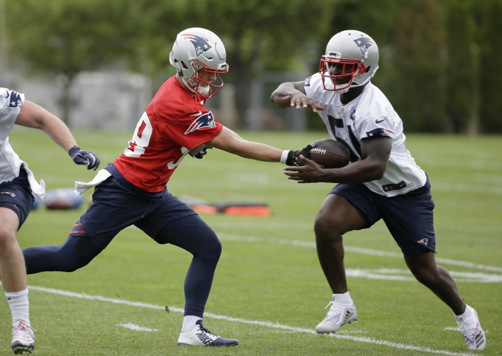 New England Patriots rookie quarterback Danny Etling, left, hands off the ball to rookie running back Sony Michel, right, during organized team activities Tuesday in Foxborough, Massachusetts.
