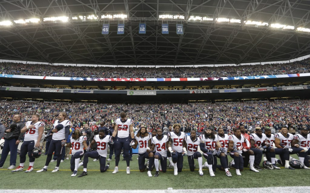 In this October 2017 photo, Houston Texans players kneel and stand during the singing of the national anthem before a game against the Seattle Seahawks in Seattle. NFL owners have approved a new policy aimed at addressing the firestorm over national anthem protests, permitting players to stay in the locker room during the "The Star-Spangled Banner" but requiring them to stand if they come to the field. The decision was announced Wednesday by NFL Commissioner Roger Goodell during the league's spring meeting in Atlanta.